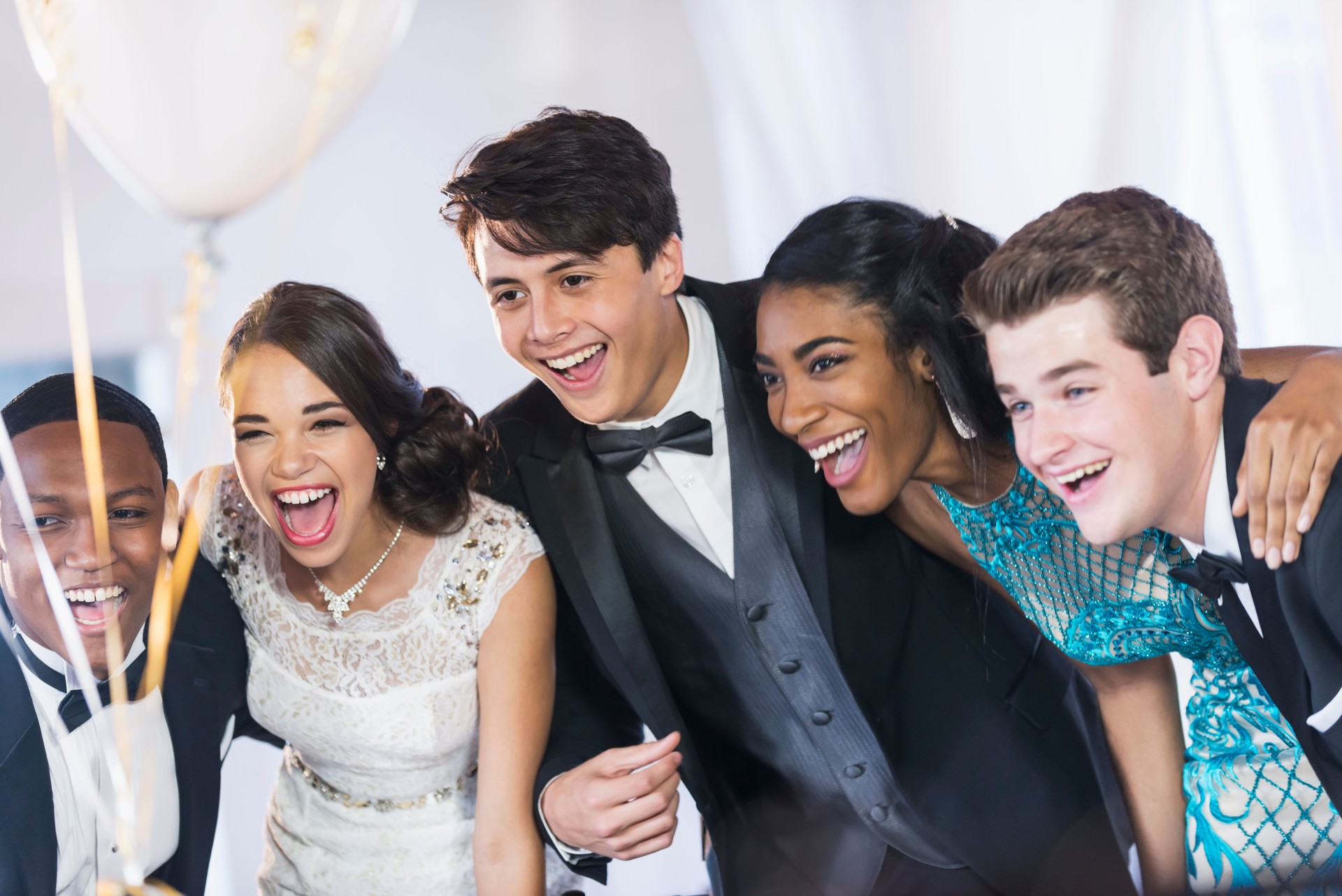 Group of teenagers at party wearing gowns and tuxedos